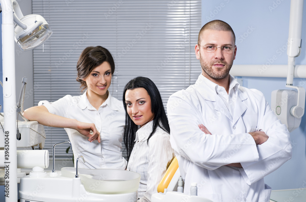 Male dentist with assistant and smiling patient at dental clinic Male dentist with assistant and smiling patient at dental clinic
