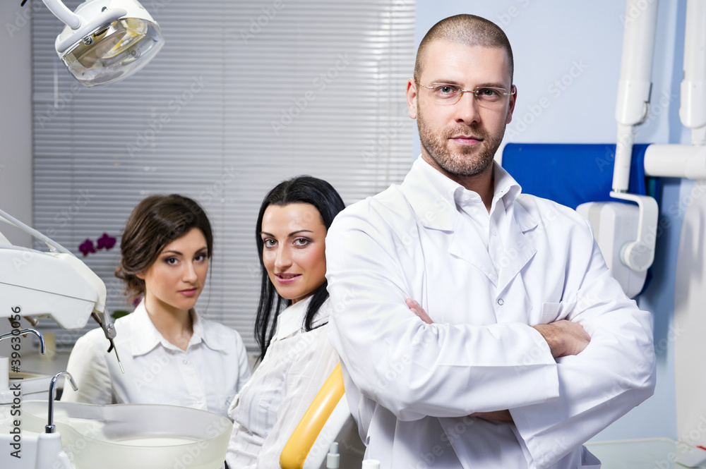 Fototapeta premium Male dentist with assistant and smiling patient at dental clinic