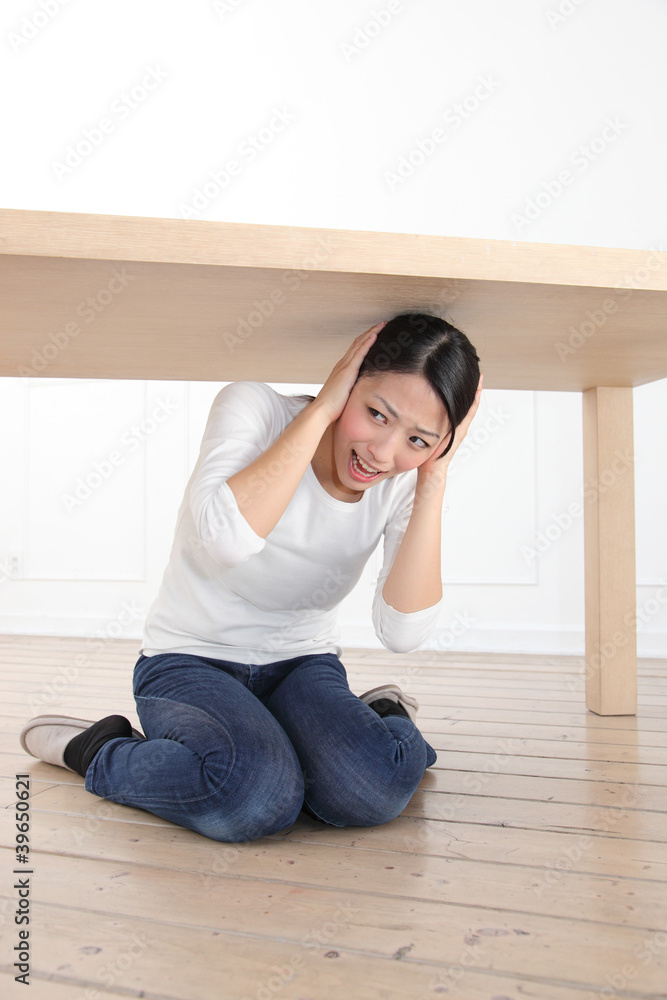 机の下に隠れる女性