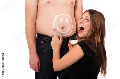 girl painting a smiley on her boyfriends belly