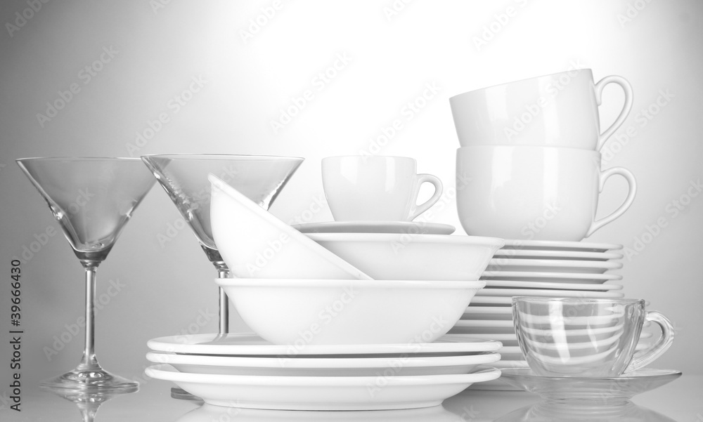 empty bowls, plates, cups and glasses on grey background empty bowls, plates, cups and glasses on grey background