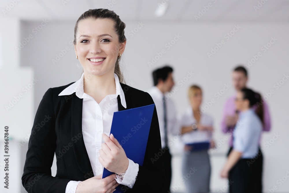 business woman standing with her staff in background business woman standing with her staff in background