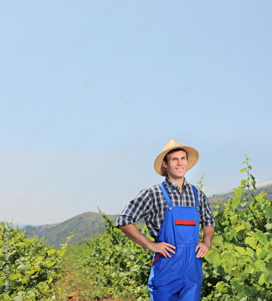 A young vintner posing with vineyard in the background