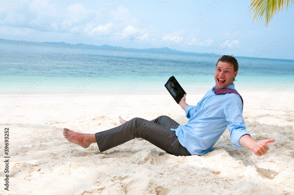 Happy business man sitting and working on the beach with tablet