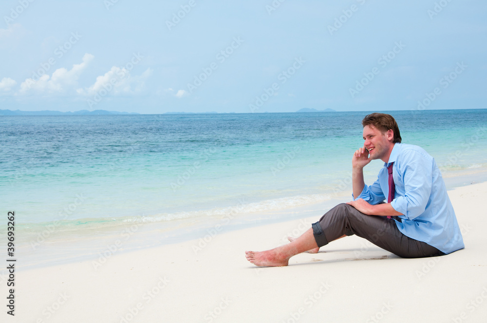 Business man calling by cell phone on the beach