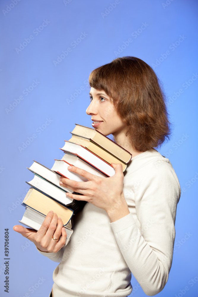 The smiling young woman holding a stack of books The smiling young woman holding a stack of books