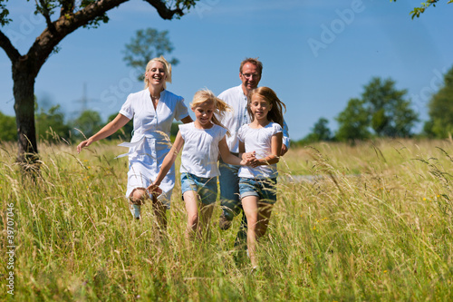 Glückliche Familie läuft in der Wiese © Kzenon