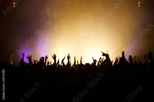 Hands in the air silhouetted against great stage lights