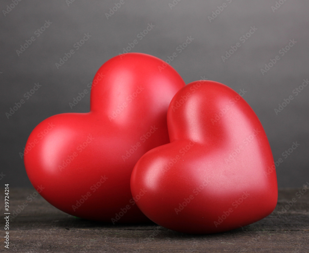 Two decorative red hearts on wooden table on grey background Two decorative red hearts on wooden table on grey background