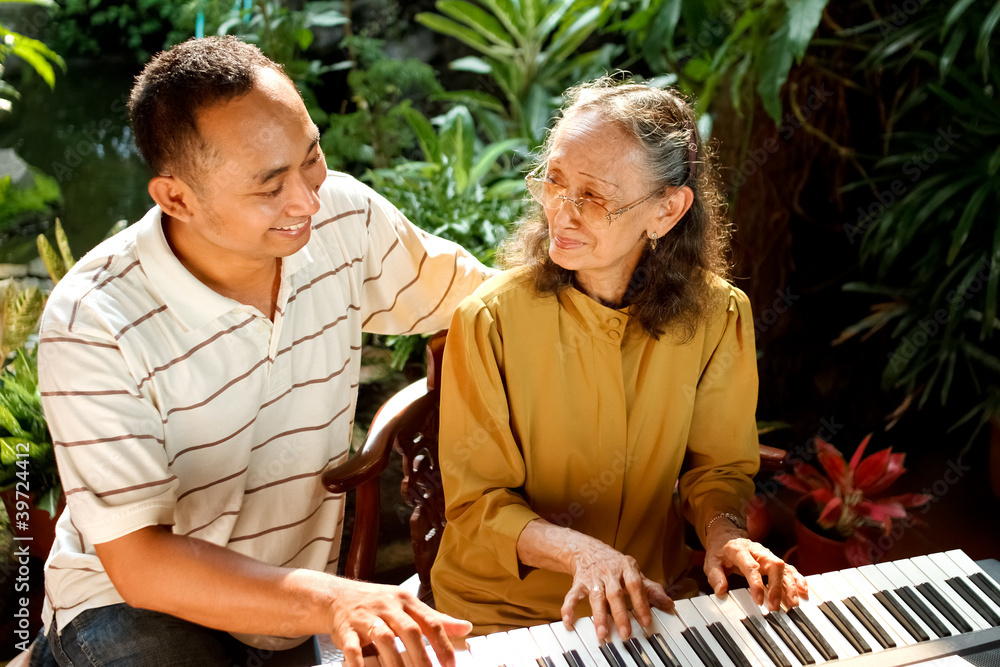 Fototapeta premium ethnic old mother and son happy playing piano together