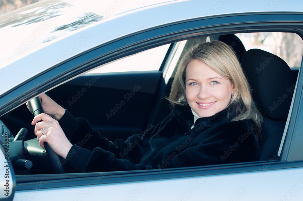 Smiling caucasian woman sitting behind the wheel of her auto
