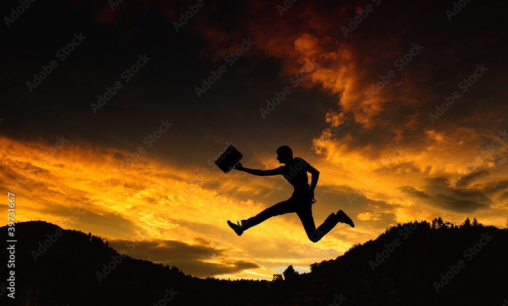 Silhouette of a man with a briefcase - jump at sunset