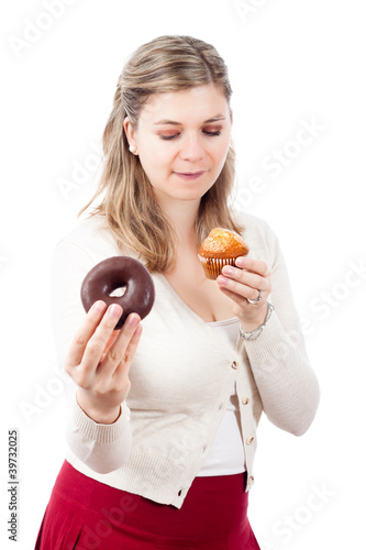 Hungry woman holding sweet muffin and donut