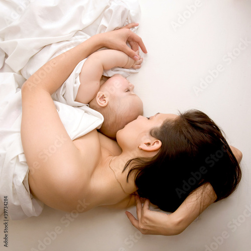 Lovely young mother and her baby sleeping in bed