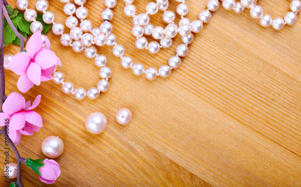 artificial pearls and pink flower on wooden background artificial pearls and pink flower on wooden background