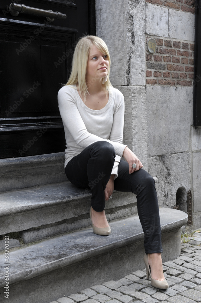 young blond woman sitting in a doorway young blond woman sitting in a doorway