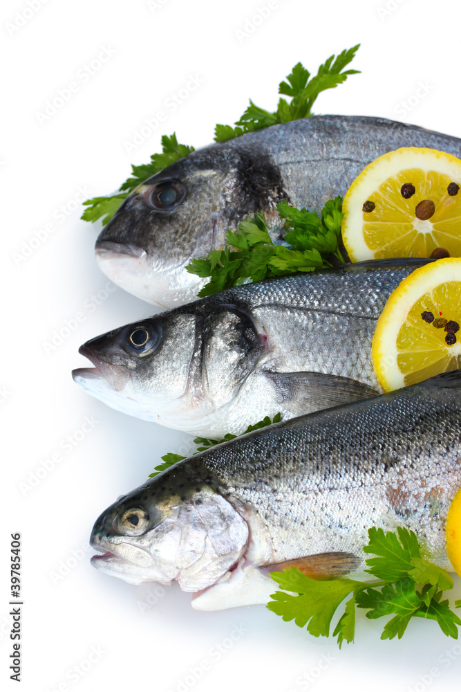 Fresh fishes with lemon, parsley and spice isolated on white Fresh fishes with lemon, parsley and spice isolated on white