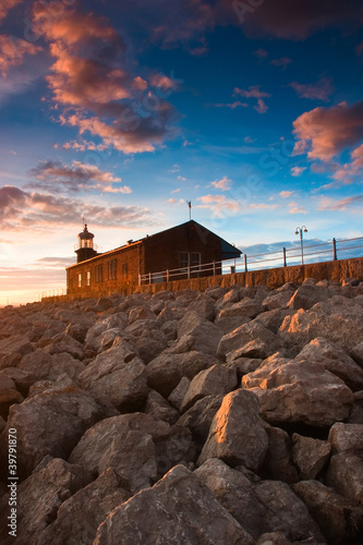 Lighthouse on the pier - Scenic view of rocky sea defences photo