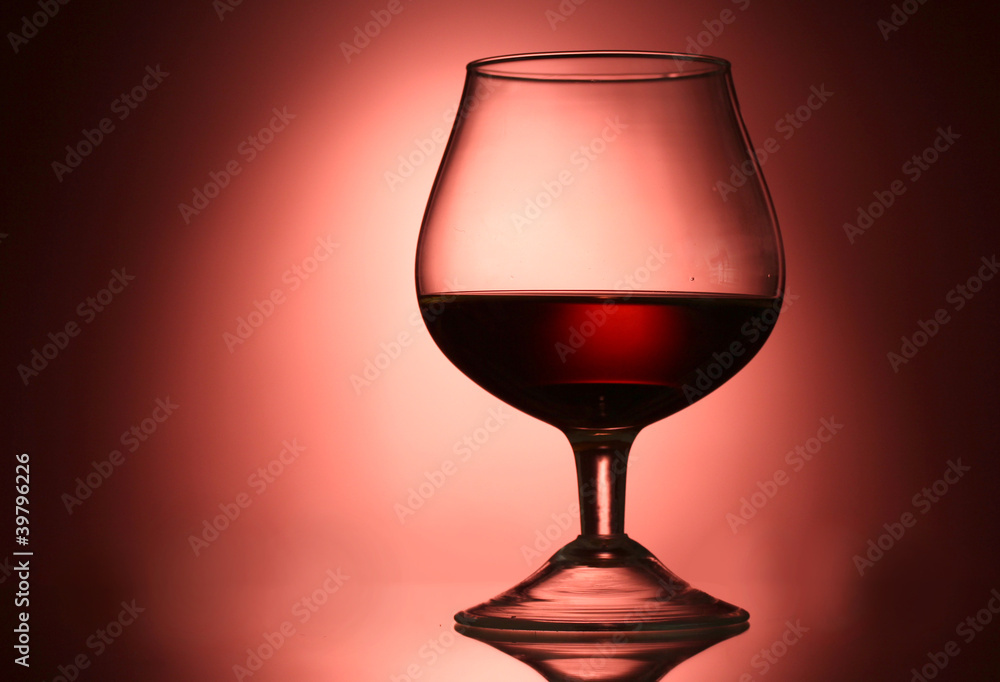 Glass of cognac on red background Glass of cognac on red background
