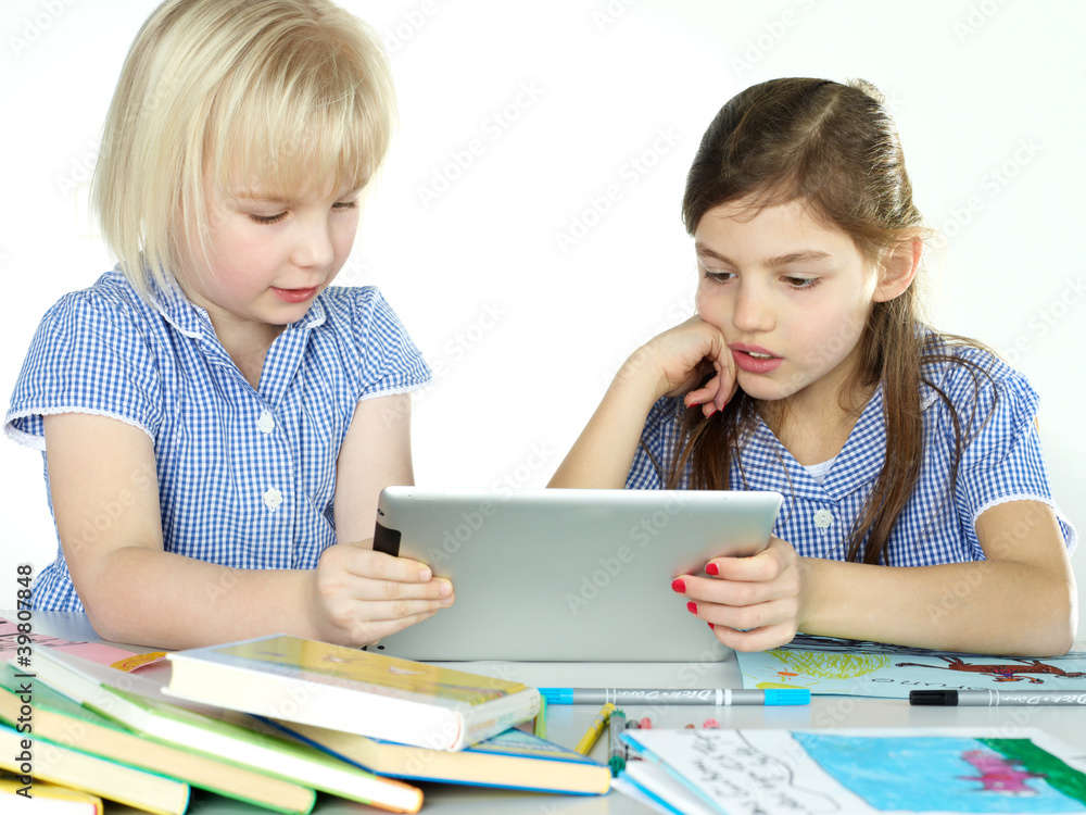 Two cute girlfriends learning with books and touchpad Two cute girlfriends learning with books and touchpad