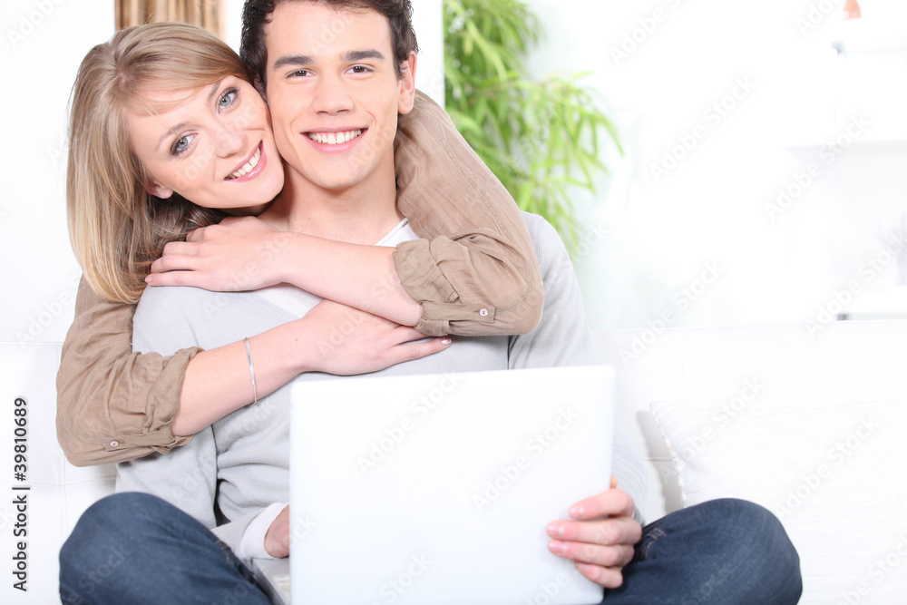 Happy couple hugging whilst surfing the Internet Happy couple hugging whilst surfing the Internet