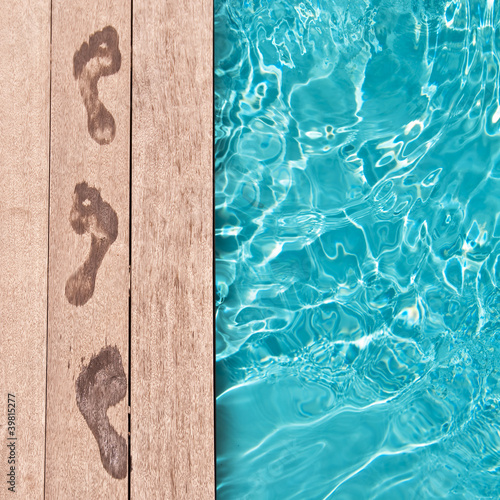 Traces de pieds nus sur un deck en bois,au bord d'une piscine, concept été