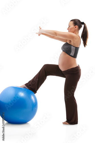 Pregnant woman doing exercises with gim ball, isolated on white