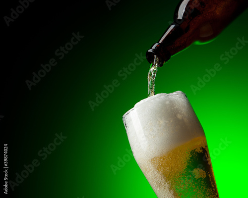 Bild auf Leinwand beer and bootle in dinamic on a green background