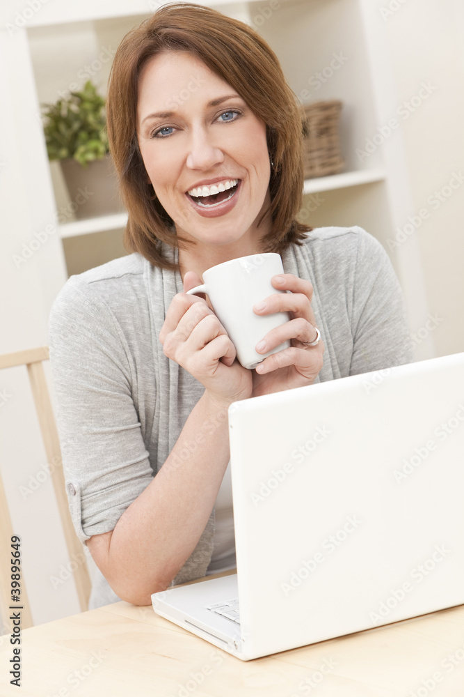 Woman Using Laptop Computer At Home Drinking Tea or Coffee Woman Using Laptop Computer At Home Drinking Tea or Coffee