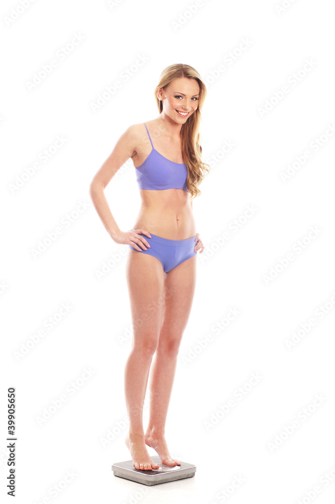 A young and fit Caucasian woman standing on scales A young and fit Caucasian woman standing on scales