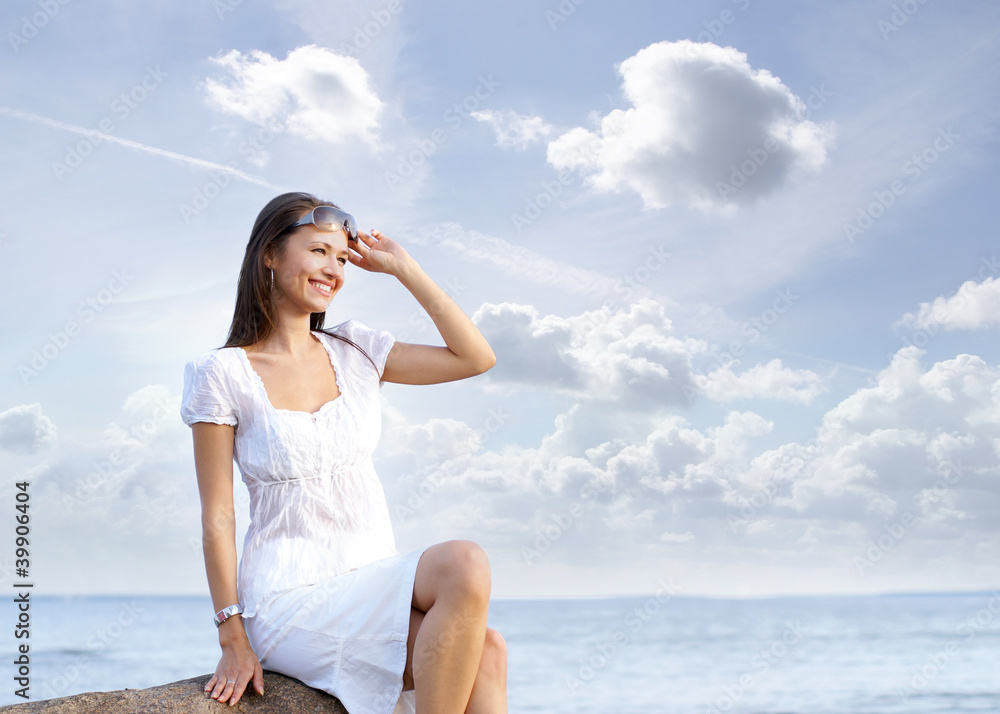 A young Caucasian woman in a summer dress near the sea A young Caucasian woman in a summer dress near the sea