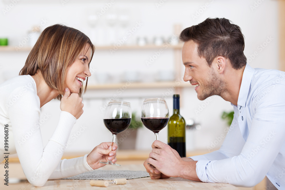 junges glückliches paar stößt mit rotwein an junges glückliches paar stößt mit rotwein an