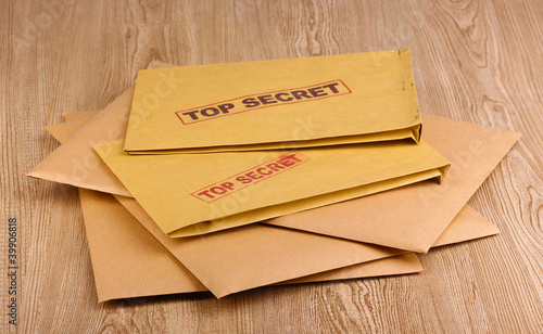 Envelopes with top secret stamp on wooden background photo