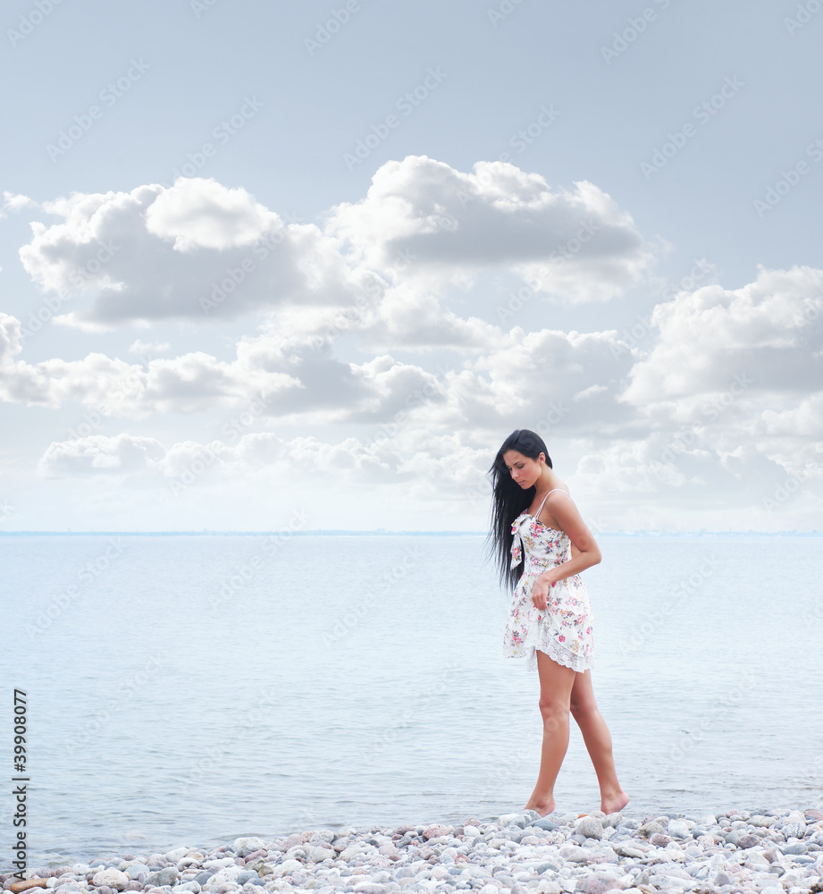 A young woman in a beautiful dress walking near the sea A young woman in a beautiful dress walking near the sea