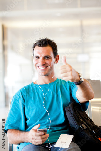 happy young traveller giving thumb up at airport