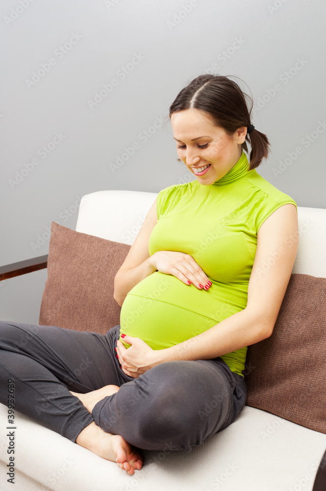 smiley pregnant woman sitting on the sofa
