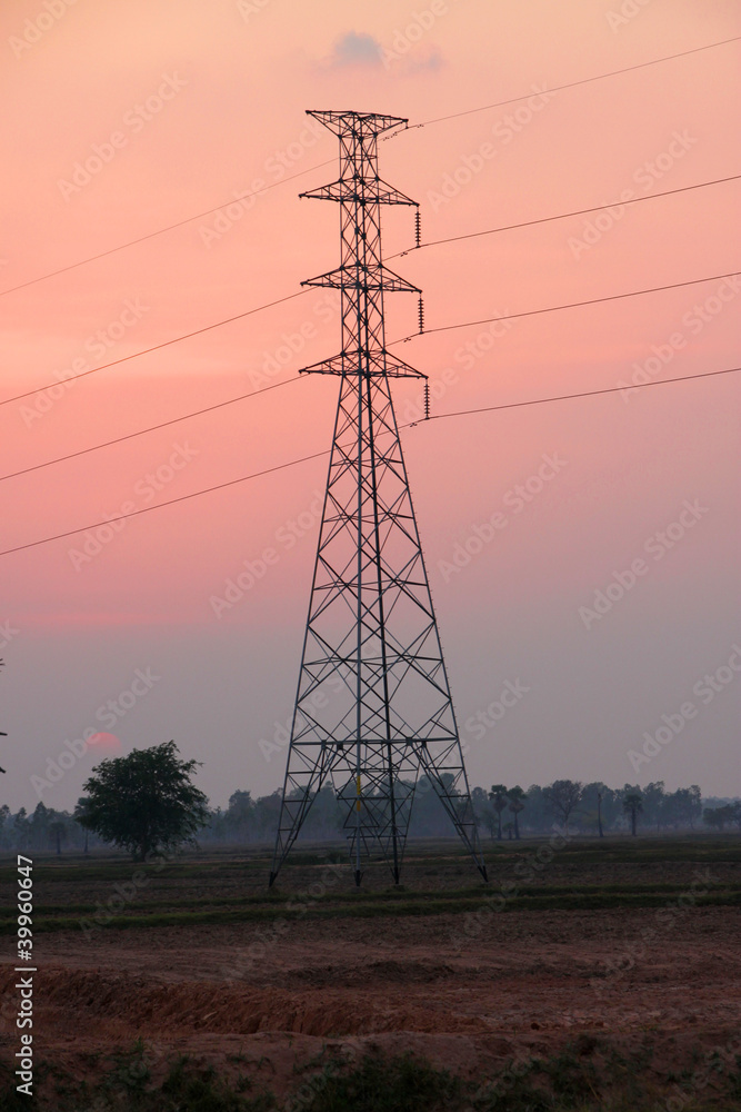 High voltage pole tower, rural field and sky after sunset