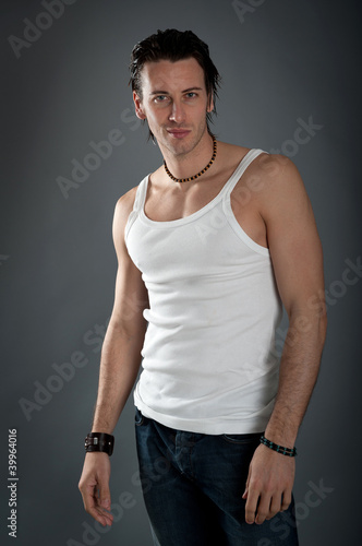 Athletic young man wearing jeans and white singlet. © pio3