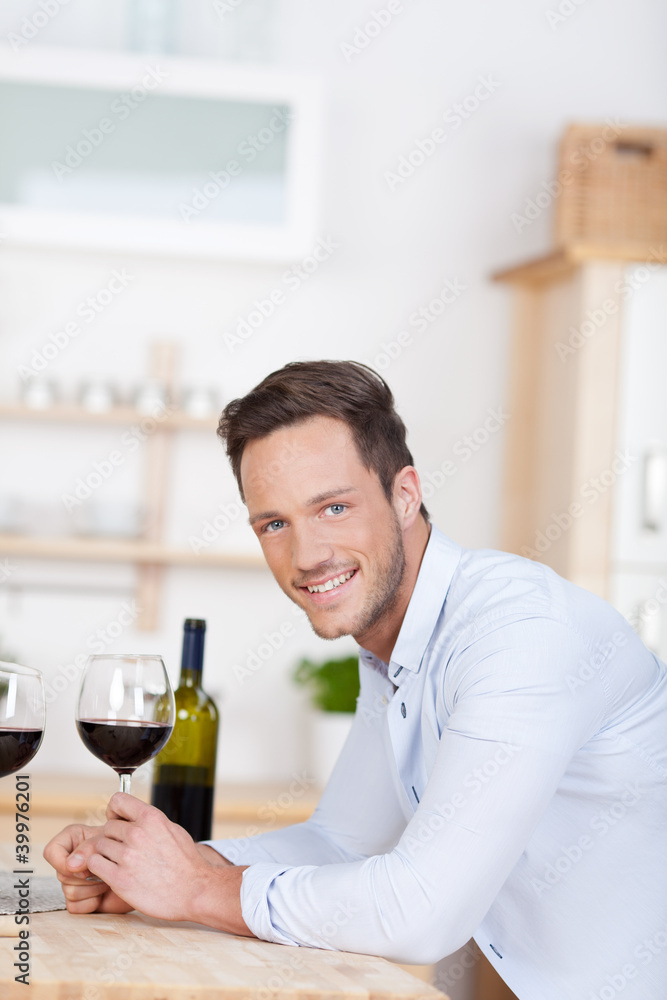 lächelnder mann mit rotwein in der küche lächelnder mann mit rotwein in der küche