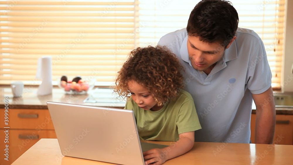 Boy using a laptop with his father Boy using a laptop with his father
