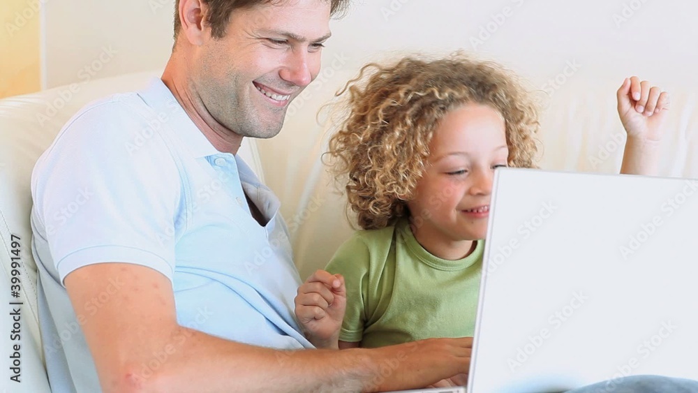 Boy laughing while watching video with his father Boy laughing while watching video with his father