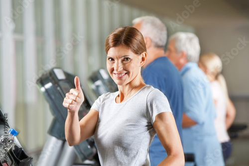Frau hält Daumen hoch im Fitnesscenter