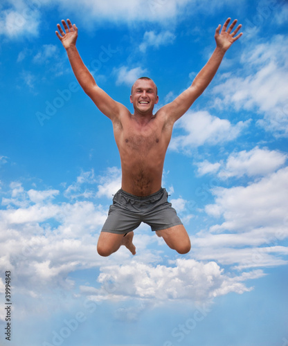 young man jumping in the air against a blue sky © EMrpize