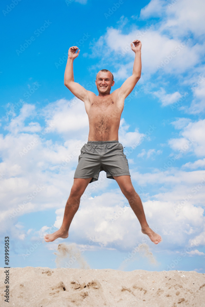 young man jumping in the air against a blue sky young man jumping in the air against a blue sky