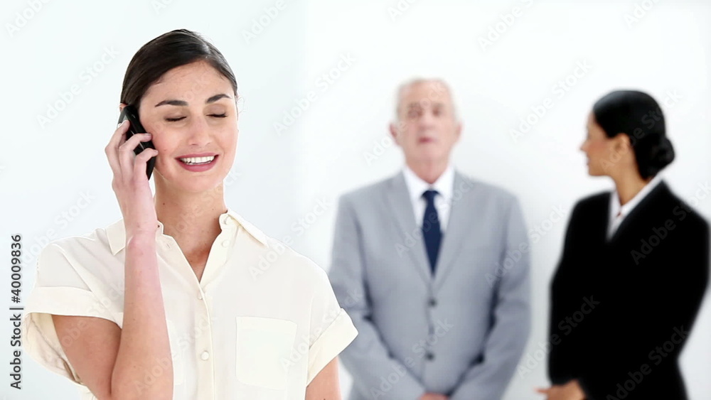 Businesswoman on the phone while her colleagues are talking Businesswoman on the phone while her colleagues are talking