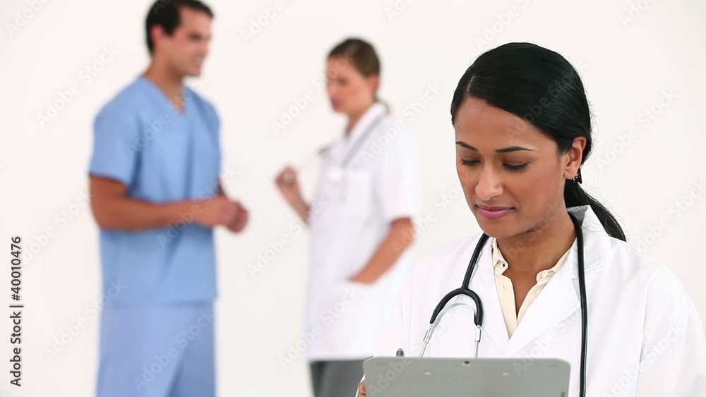 Female doctor posing in front of her colleagues Female doctor posing in front of her colleagues