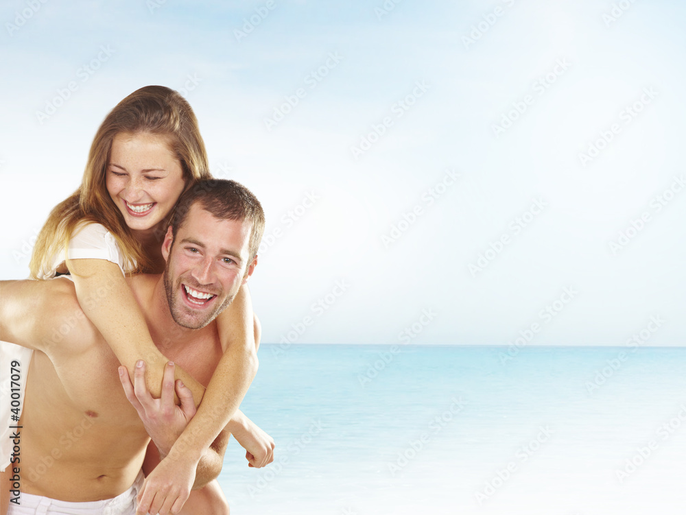 Smiling young couple piggybacking at beach Smiling young couple piggybacking at beach