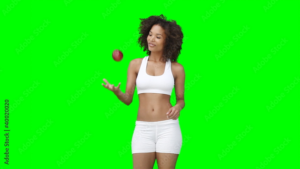 A woman walking and throwing an apple up and down A woman walking and throwing an apple up and down
