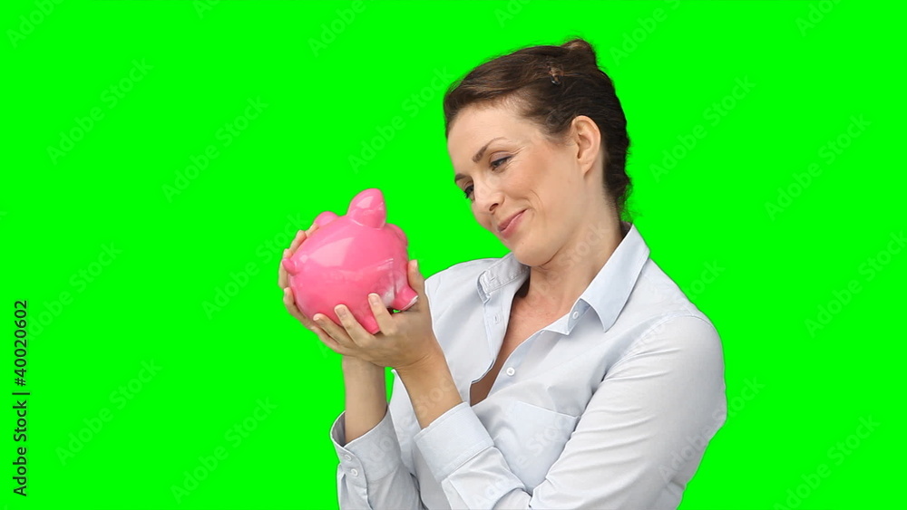A smiling woman kissing her piggy-bank A smiling woman kissing her piggy-bank