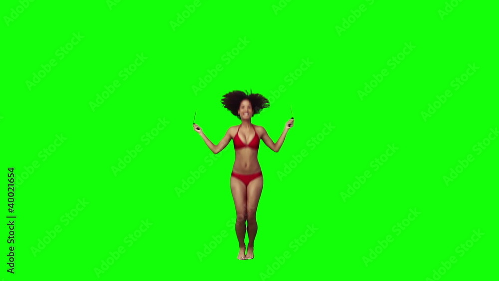 A woman wearing a bikini is using a skipping rope A woman wearing a bikini is using a skipping rope